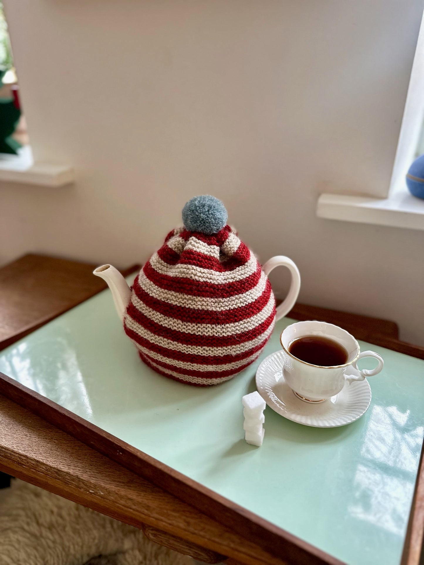 Håndstrikket tehætte med pompon - rød og beige stribet