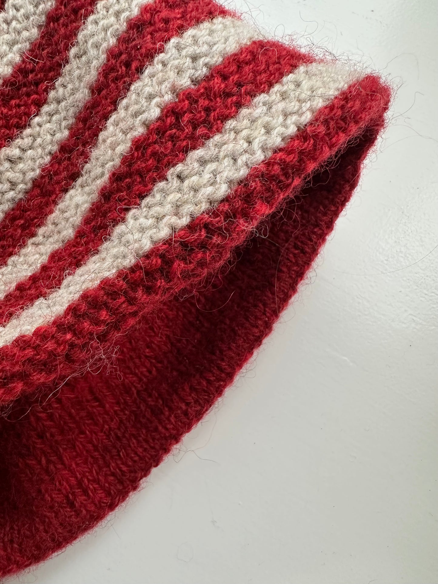 Håndstrikket tehætte med pompon - rød og beige stribet