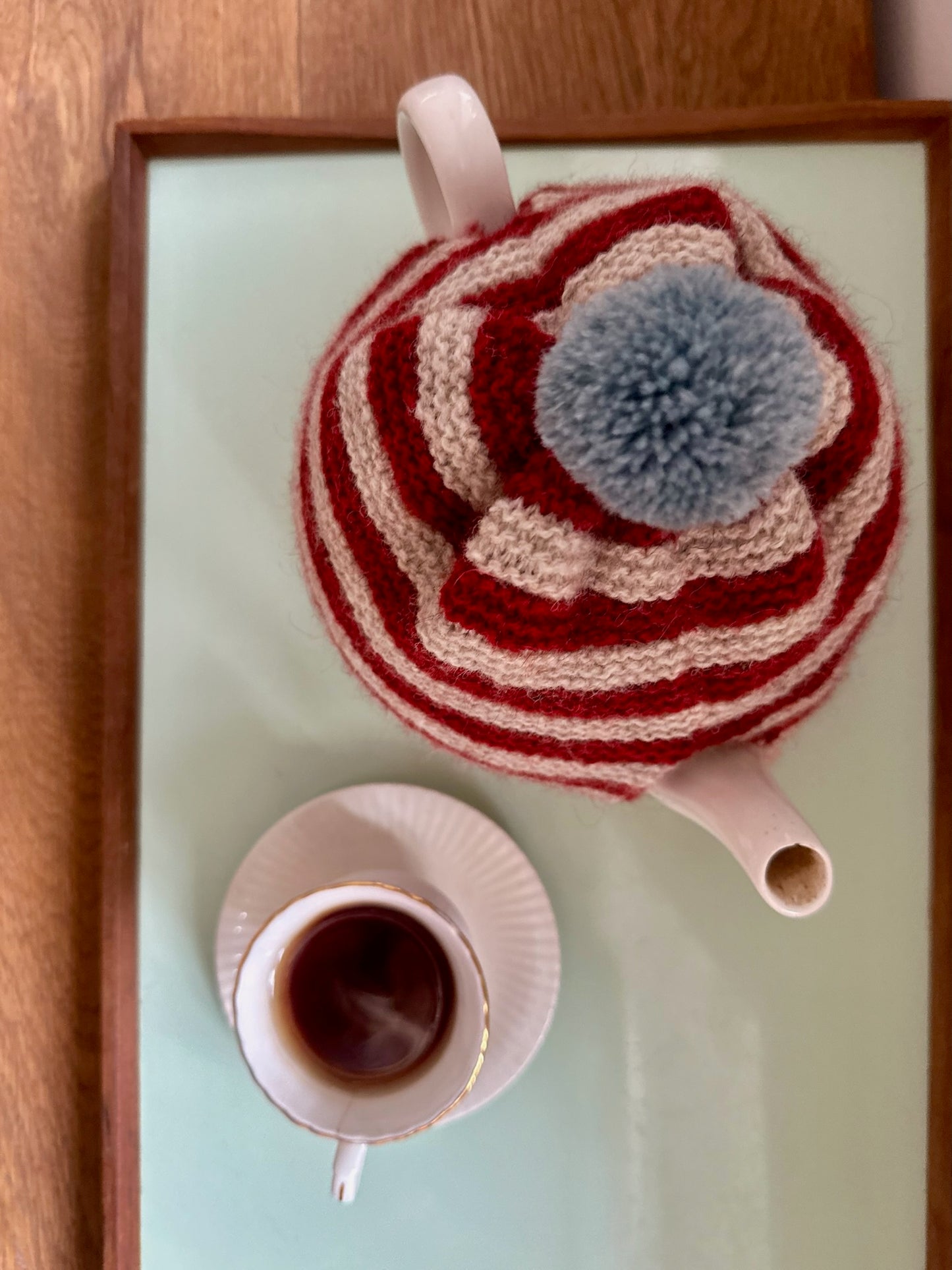 Håndstrikket tehætte med pompon - rød og beige stribet