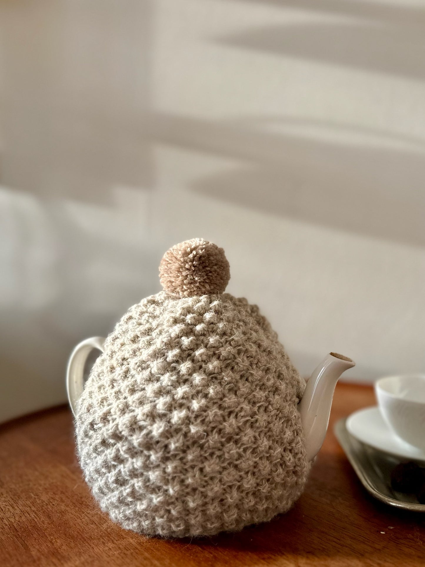 Håndstrikket tehætte med pompon - beige uld