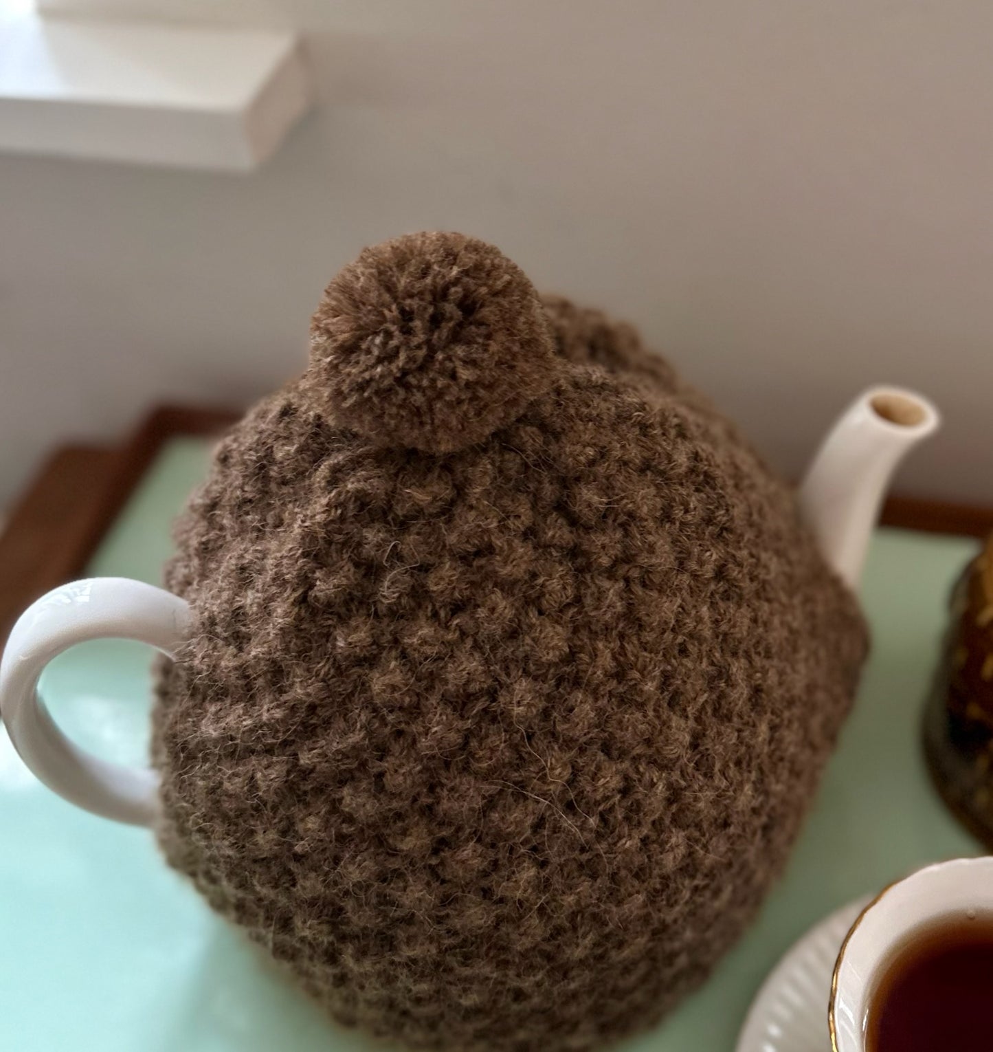 Håndstrikket tehætte med pompon - brun uld